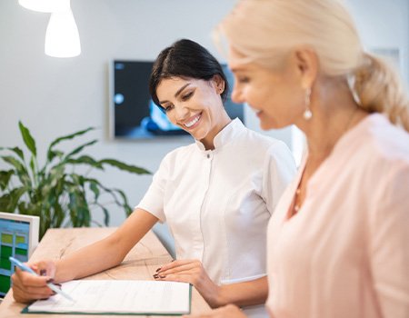 Smiling dental assistant showing patient forms