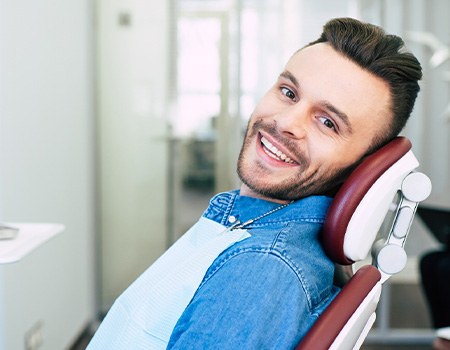 a smiling man sitting in a dental chair