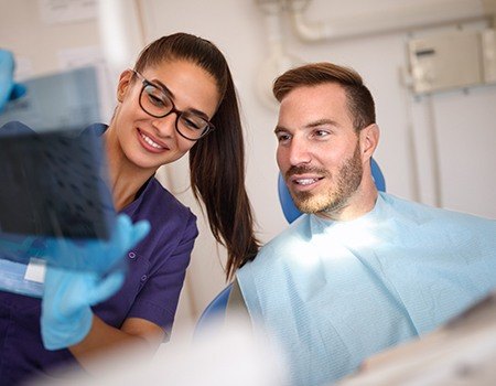 Man in dental chair looking at x-rays