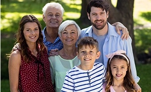 Three generations of family smiling together outdoors