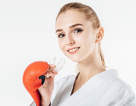 Girl with boxing gloves placing mouthguard