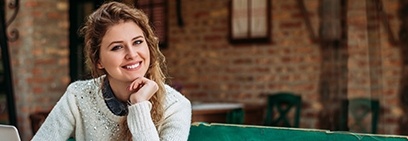 Woman in white sweater smiling outdoors