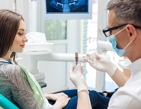 Dentist showing patient dental implant model