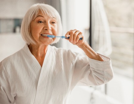 Senior woman brushing her teeth in the bathroom