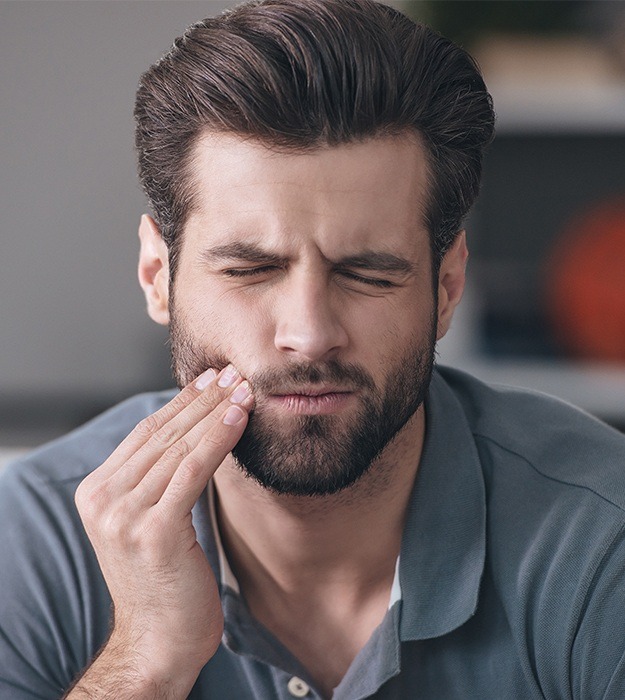 Man in pain holding cheek