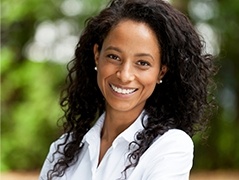 Woman in white collared shirt smiling outdoors