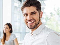 Man in white collared shirt grinning outdoors