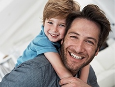 Smiling dad giving son a piggy back ride