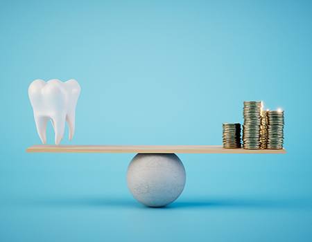 A model tooth and a stack of golden coins on a balance beam