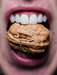 person cracking nut with teeth 