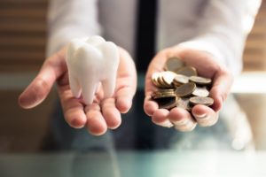 Spring House dentist holds pile of coins and model tooth 