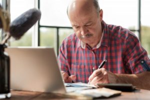 mature man writing on notepad 