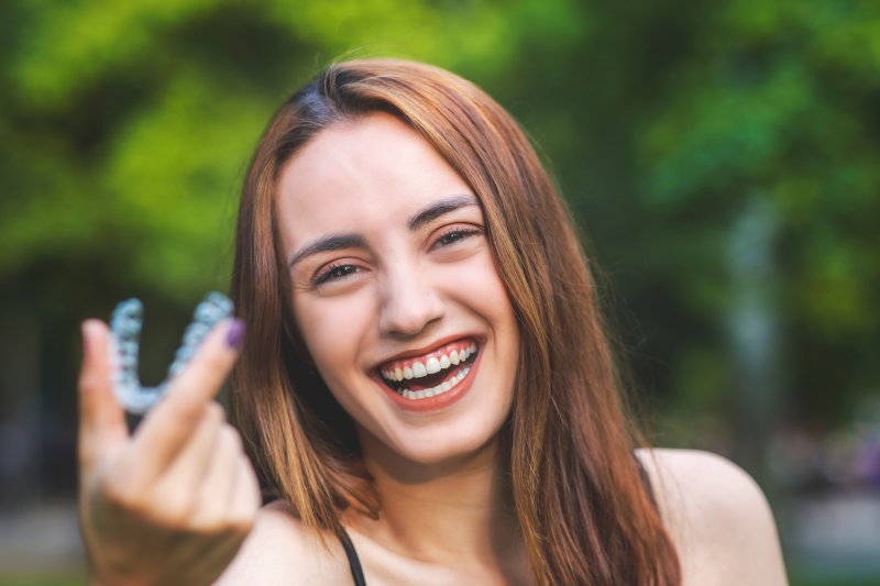 person holding Invisalign and smiling