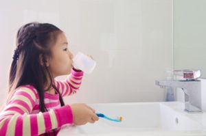 A child rinsing her mouth after brushing her teeth.