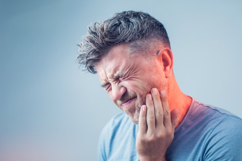 person with toothache or sinus pressure holding cheek