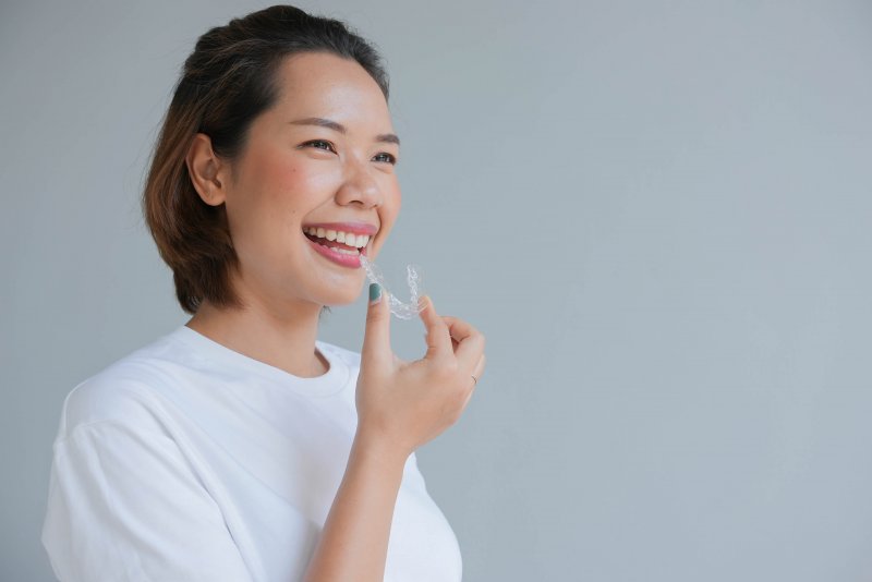 young woman holding an Invisalign aligner