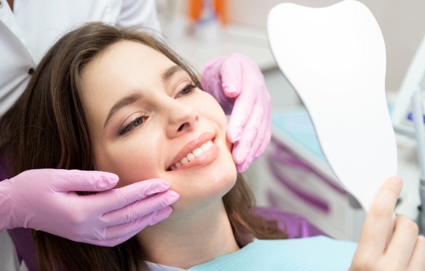 Woman with white smile in dental chair admiring mirror